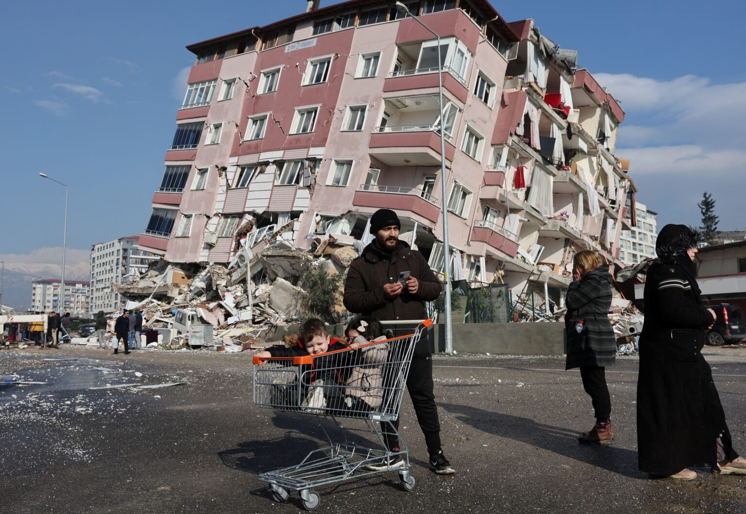 Des personnes face à un bâtiment en partie écroulé, dans la province du Hatay en Turquie le 7 février 2023 ©BelgaImage